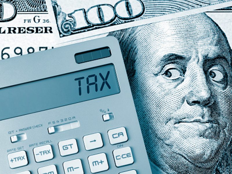 Tax. Benjamin Franklin looking calculator on One Hundred Dollar Bill.